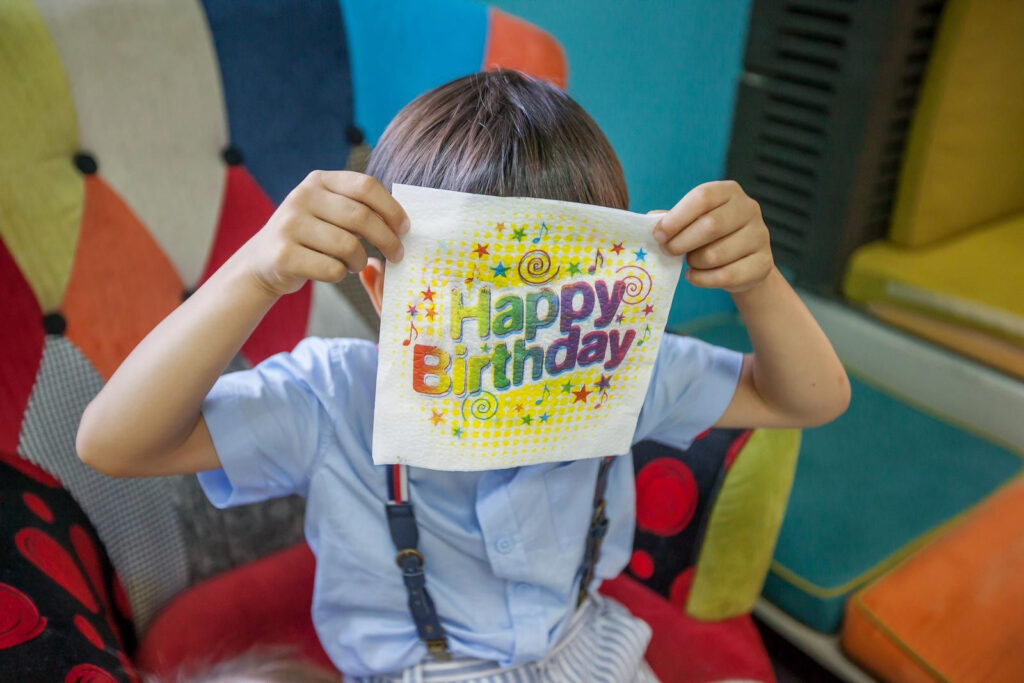 Dete se igra i krije iza salvete na rođendanskoj proslavi – spontani i zabavni trenuci zabeleženi profesionalnim fotografisanjem