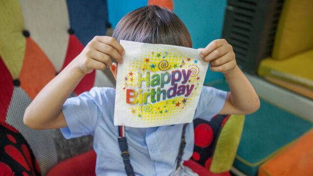 Dete se igra i krije iza salvete na rođendanskoj proslavi – spontani i zabavni trenuci zabeleženi profesionalnim fotografisanjem